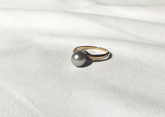 May include: A gold ring with a single gray pearl set in the center.